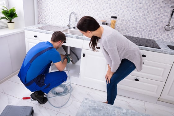 A technician working on a sink with a customer watching