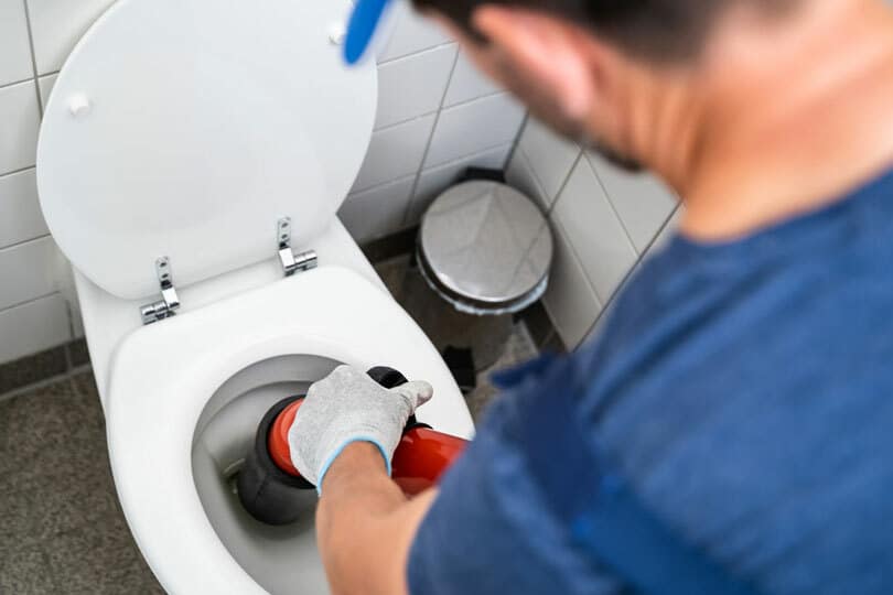 A plumber working on a toilet