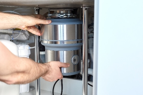 A plumber repairing the garbage disposal