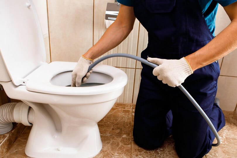 A technician hydrojetting a toilet