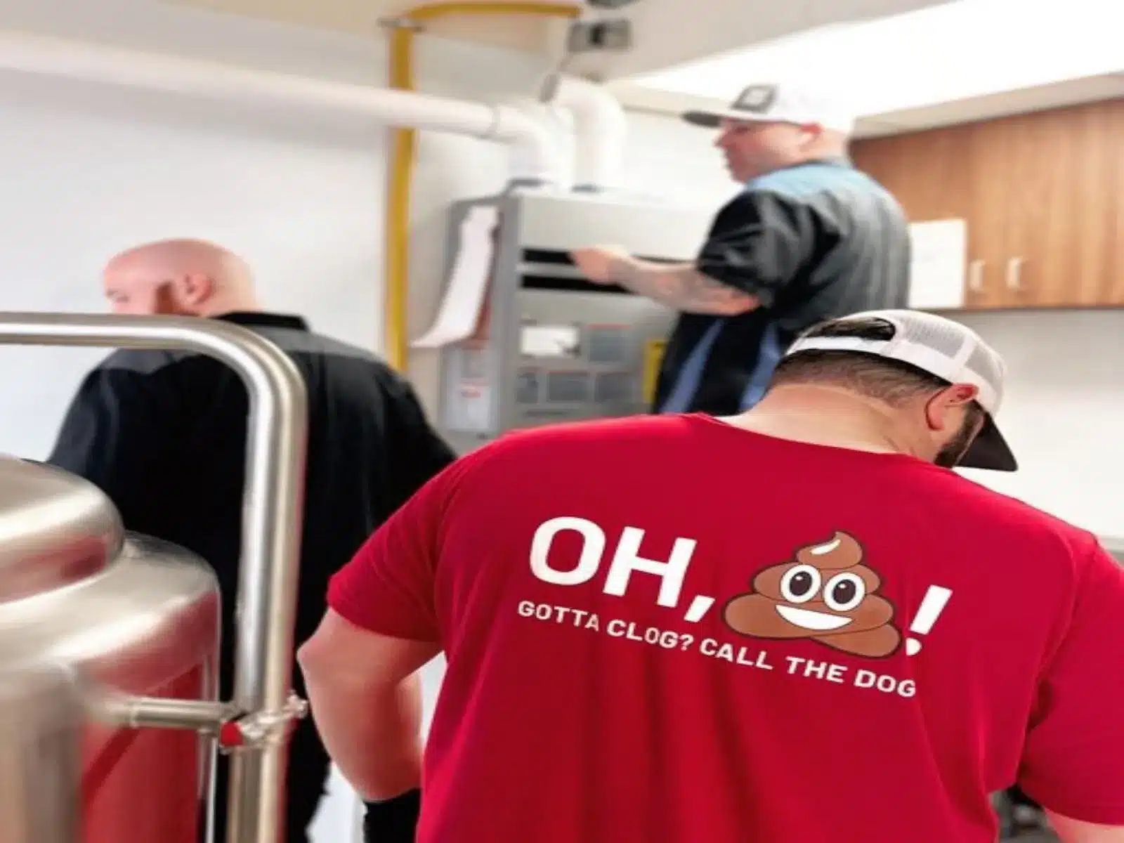 Bulldog Rooter technicians working in a house- one is wearing a shirt that says "Oh poop emoji! Gotta clog? Call the Dog!"