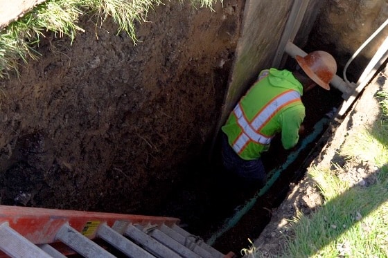 A technician working outside on a drain