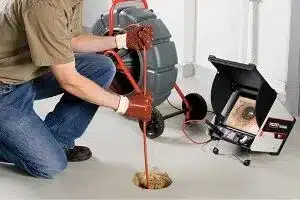 A person using a cable snake to rooter a floor drain