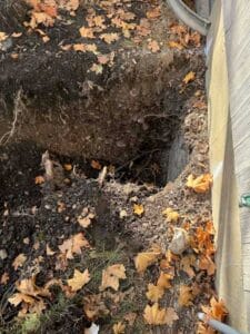 Up close of sewer line excavation where pipes connect to the home