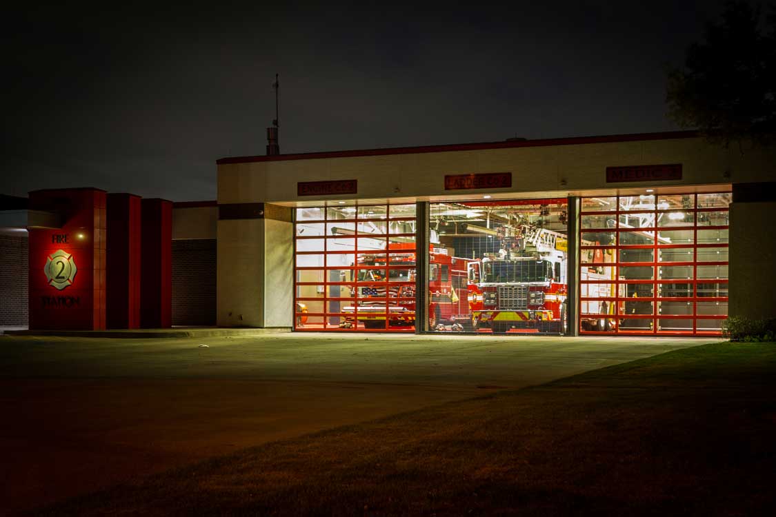 A photo of a fire station with trucks ready to respond at night