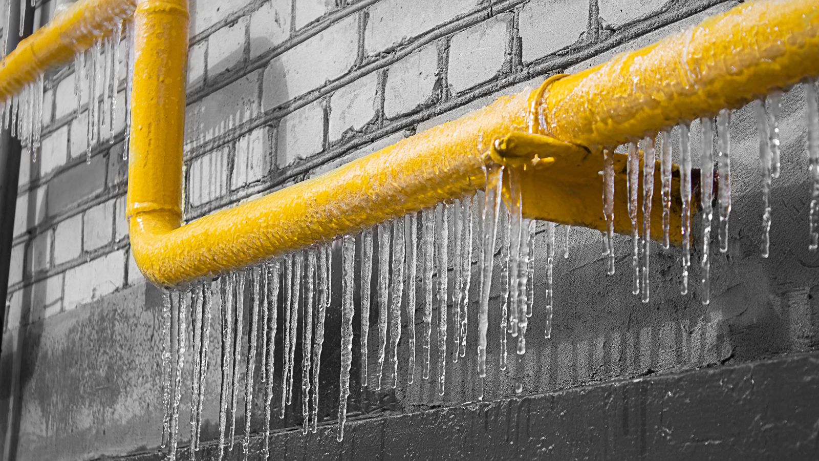 Yellow pipes frozen over with icicles