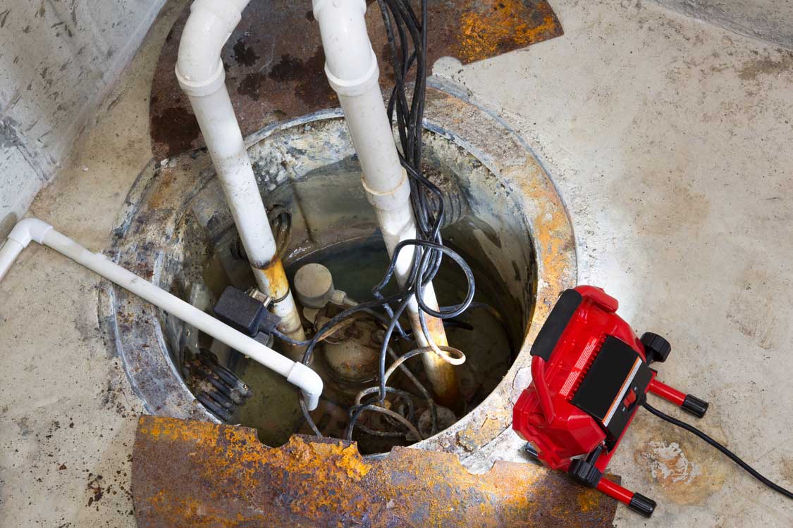 A sump pump in a basement crawl space being repaired