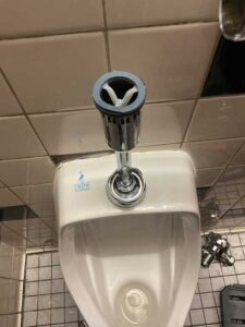 A urinal with flush removed to be repaired